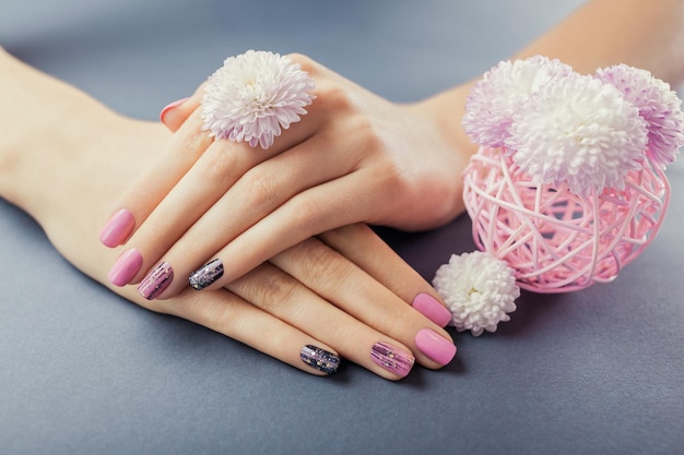 Pink and black manicure on female hands with flowers Nail art and design Body care