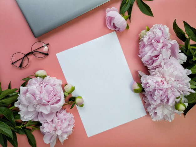 Pink business lady desk with a piece of paper laptop and flowers