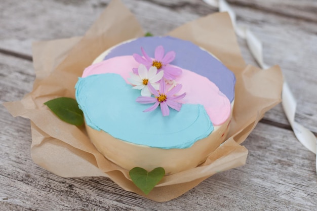 Pink cake with flowers delicate beige wedding tart decorated with cosmos on wooden background