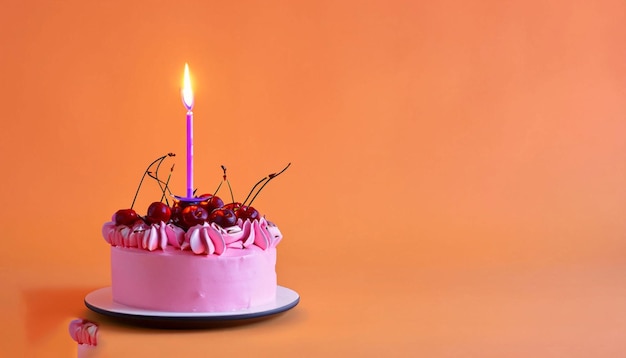 A pink cake with a lit candle is on a orange background.