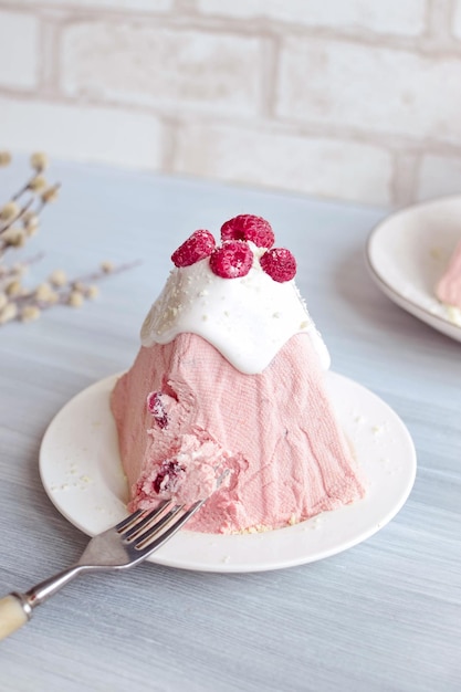 A pink cake with white frosting and a fork on a plate with a strawberry cake on it.