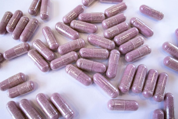 Pink capsules with additives on a white background Pills and medicines Tart cherry additives vitamins minerals plant extracts and other beneficial substances