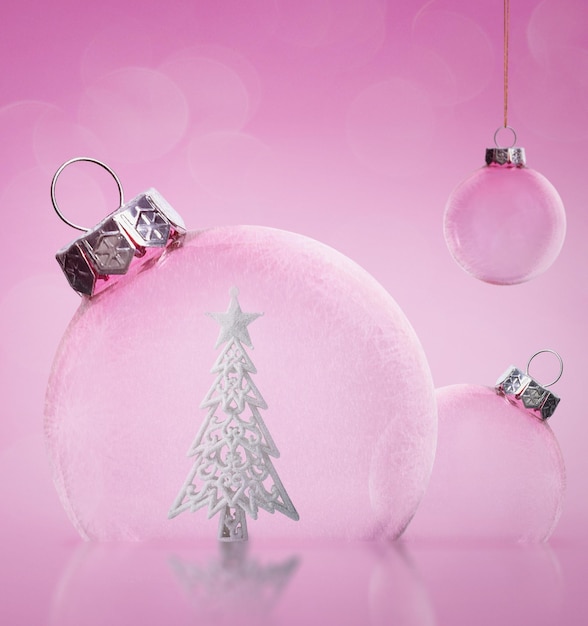 Pink Christmas transparent balls with a Christmas tree inside on a pink background