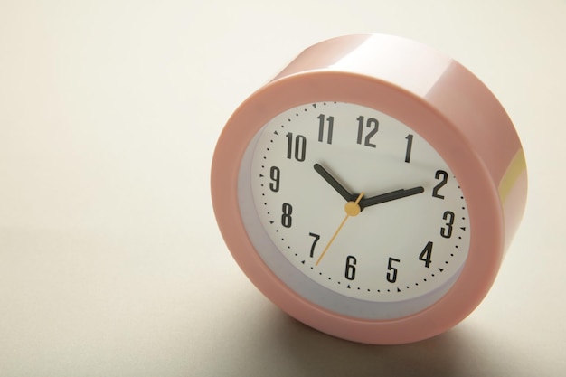 Pink clock on grey background Top view