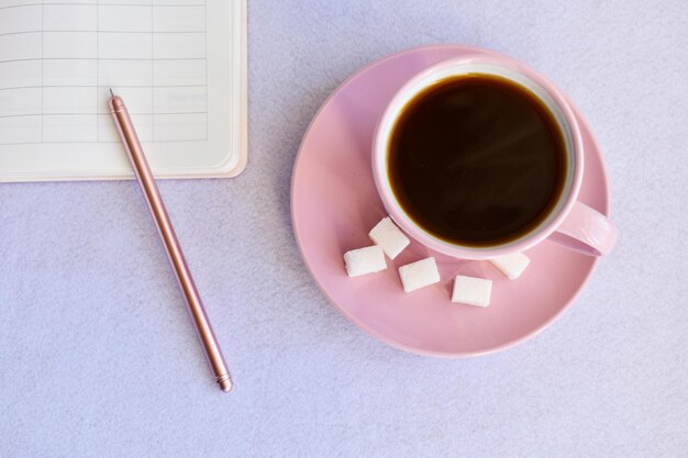 Pink cup black of coffee notebook pen Overhead view Isolated on white Flat lay top view