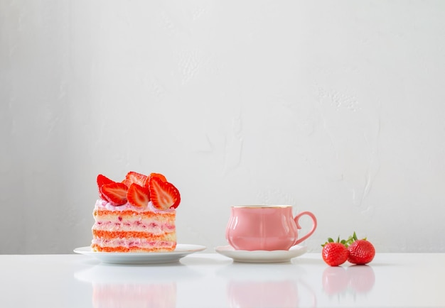 pink cup of coffee and strawberry cake on white background