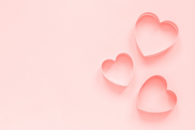 Pink cutters cookies in heart shape on pastel pink background, colar toned. Love romantic pattern