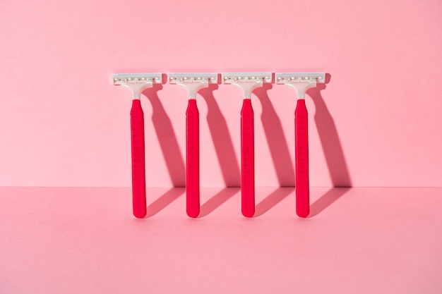 Pink disposable razors on pink background with copy space