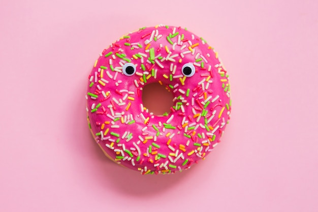 Pink donut with eyes on a pink background