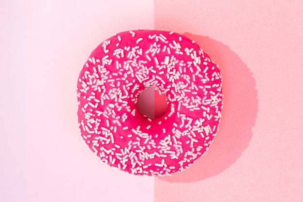 Pink donut with icing on pastel pink background