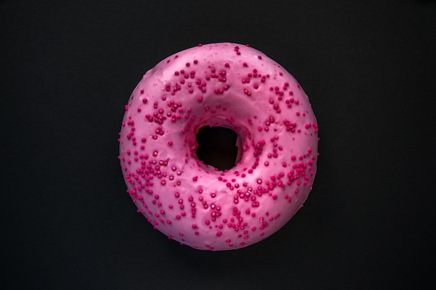 A pink donut with pink sprinkles on it