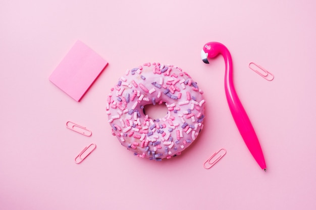 Pink doughnut and Flamingo pen on pink. Top view Flat lay.