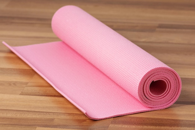 Pink exercise mat on wooden floor. Home workout concept