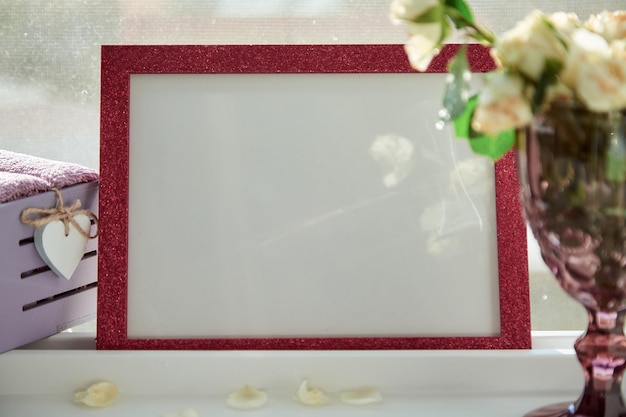 Pink frame mock up with sunlight and wineglass with white roses Selective focus High quality photo