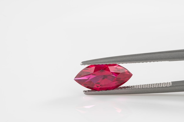 A pink gem is being measured by a pair of tongs.