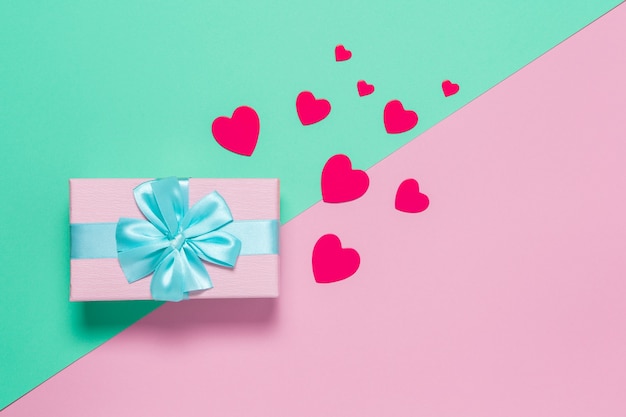 Pink gift box with blue bow on pastel two-color background pink and mint, copy space, flat lay. March 8, February 14, birthday, St. Valentine's, Mother's, Women's day celebration concept. Horizontal