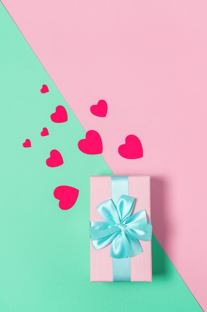 Pink gift box with blue bow on pastel two-color background pink and mint, copy space, flat lay. March 8, February 14, birthday, St. Valentine's, Mother's, Women's day celebration concept. Vertical