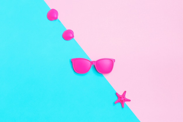 Pink glasses and seashells on colorful.