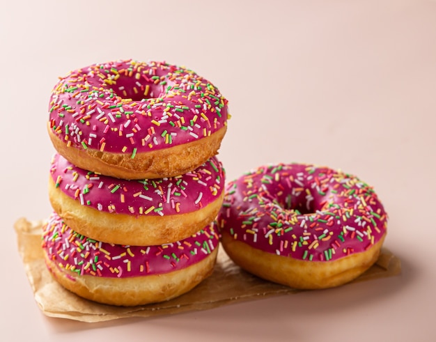 Pink glaze dessert with colorful sprinkles on brown paper.