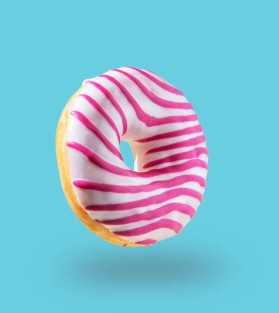 Pink glazed  donut flying on blue background. Levitation concept food. Colorful image