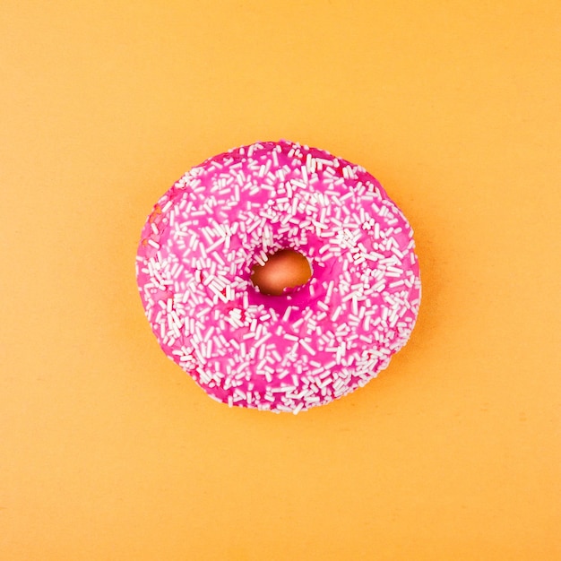 Pink glazed donut on orange background Flat lay Creative concept