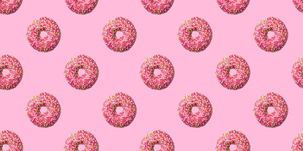 Pink glazed donut seamless pattern on pink background. Concept food. Top view.