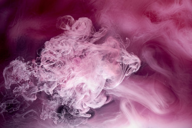 Pink gray smoke on black ink background colorful fog abstract swirling touch ocean sea acrylic paint pigment underwater