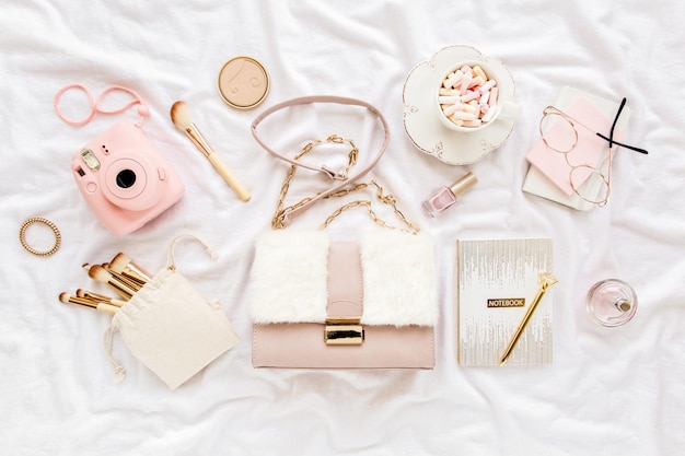 Pink handbag camera makeup brushes cosmetics sunglasses accessories on white background flat composi