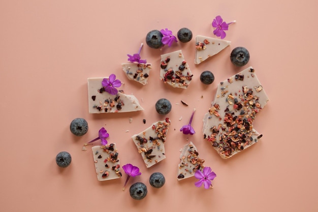 Pink handmade chocolate with berries and flowers broken bars with hazelnuts almond and raspberry