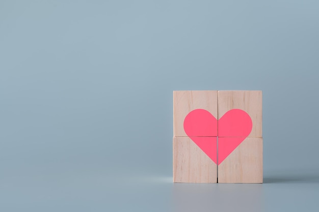 Pink heart in cube wooden blocks light blue background healthcare and emotional concept