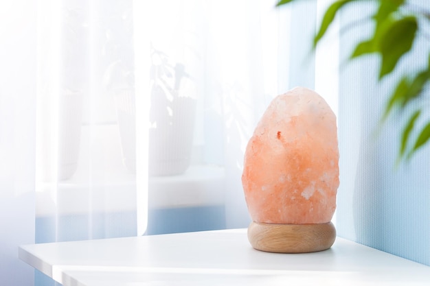 Pink himalayan rock lamp on white table in sunny day