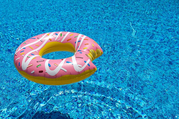 Pink inflatable donut doughnut floating mattress in swimming pool. Beach pool accessories. Summer holiday concept.