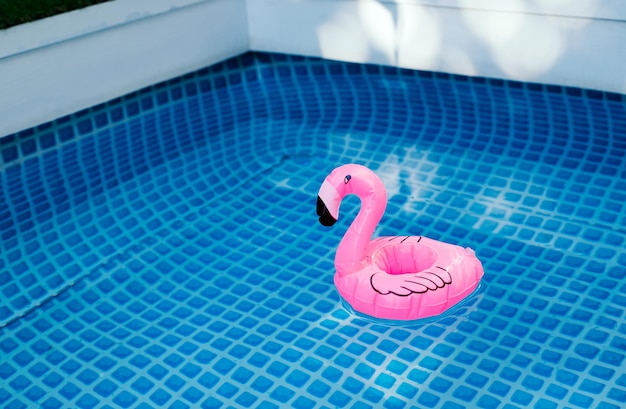 Pink inflatable flamingo in pool water for summer beach background Minimal summer concept