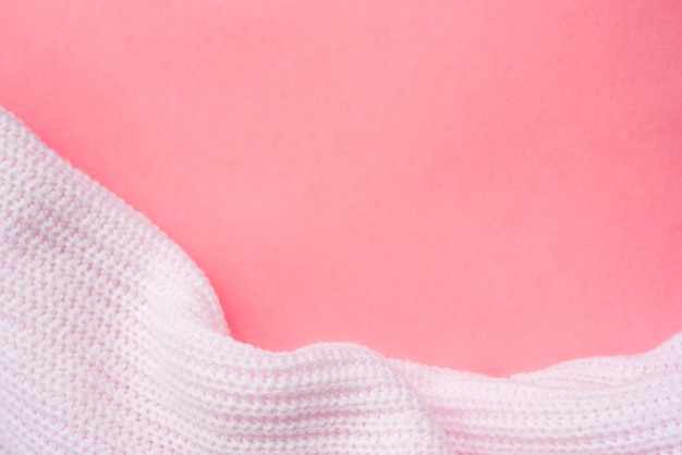 Pink knitted clothes on a pink paper background