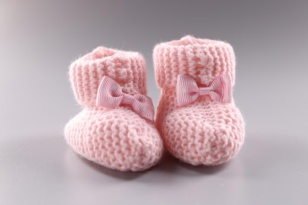 Photo pink knitted slippers for newborn on gray background