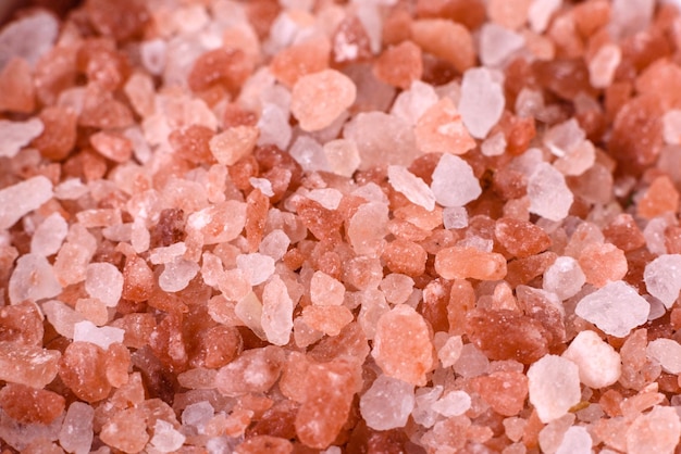 Pink large Himalayan salt in a white saucer on a black concrete background