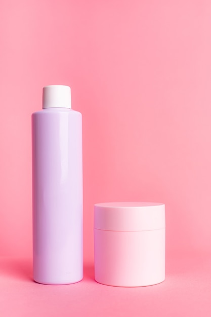 Pink and light purple cosmetic bottles on a pink background