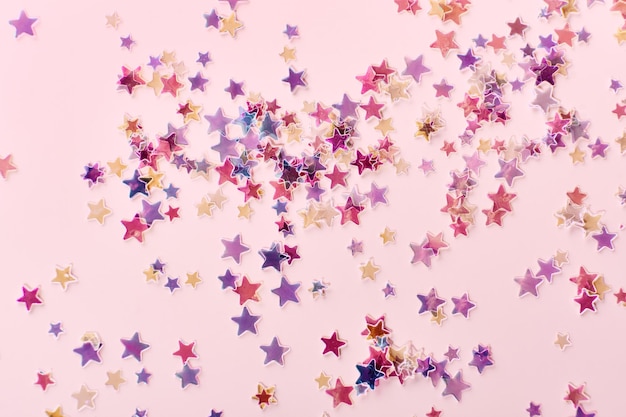 Pink and lilac holographic Stars Glitter Confetti on pink background Festive backdrop