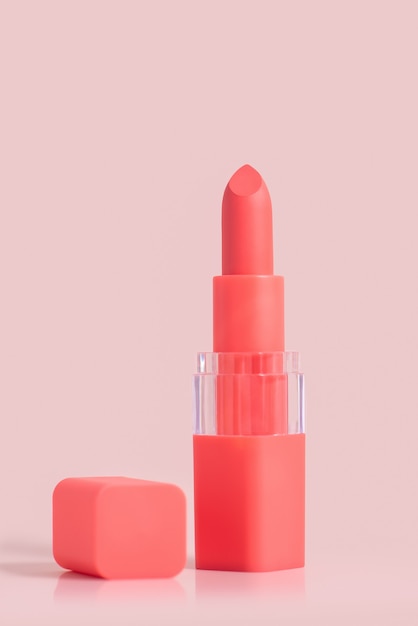 Pink lipstick in a lid of the same color with a cap next to it