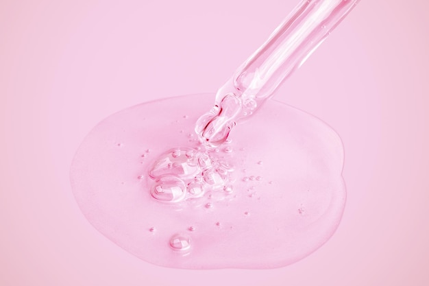 A pink liquid with a drop of liquid being poured into it.