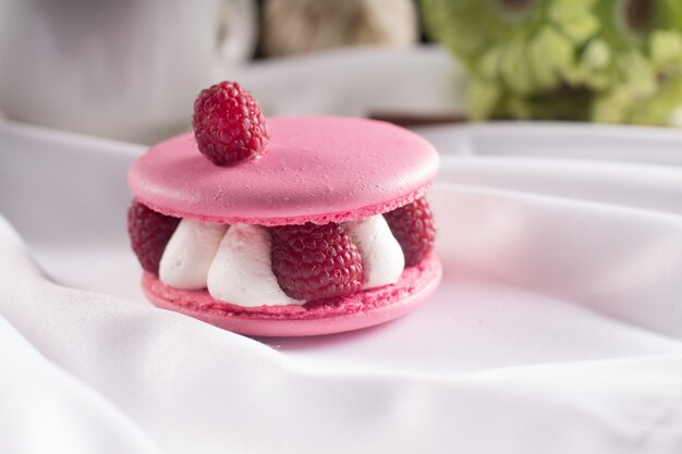 Pink macarons with vanilla cream, fresh raspberries