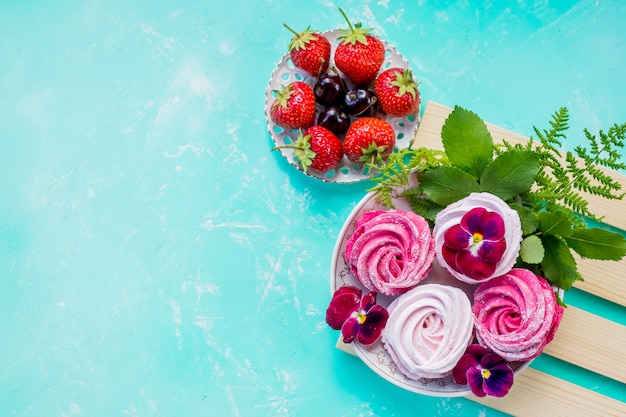 pink meringue cookies with berries for dessert