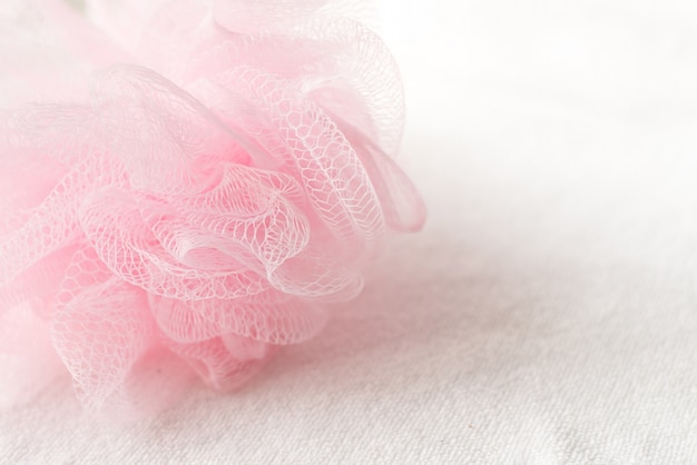 Pink mesh shower sponge on white background.