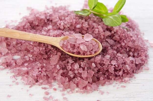 Pink mineral sea aroma bath salt crystals in wooden spoon with green mint leaf Aromatherapy and body care