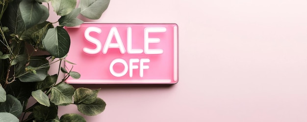 Photo pink neon sale sign with 25 off message surrounded by green leaves on a pastel pink background