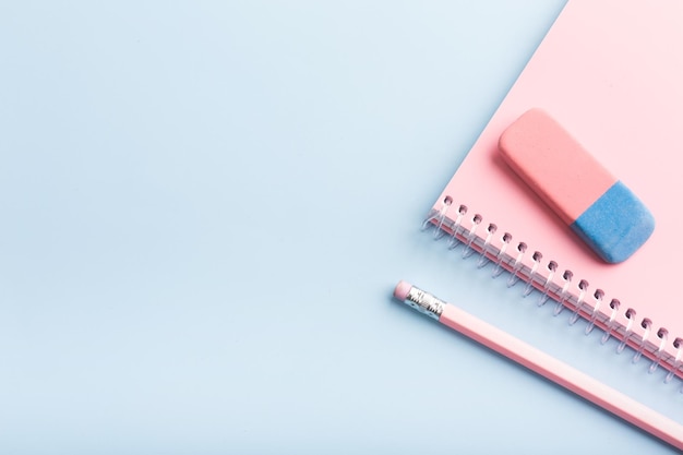 Pink notebook and pencil on a blue background Place for your text