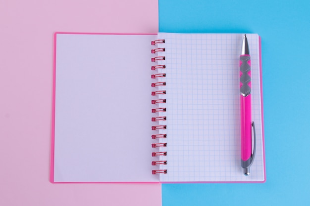 Pink notebook  with a pink pen on a bright multi-colored background.