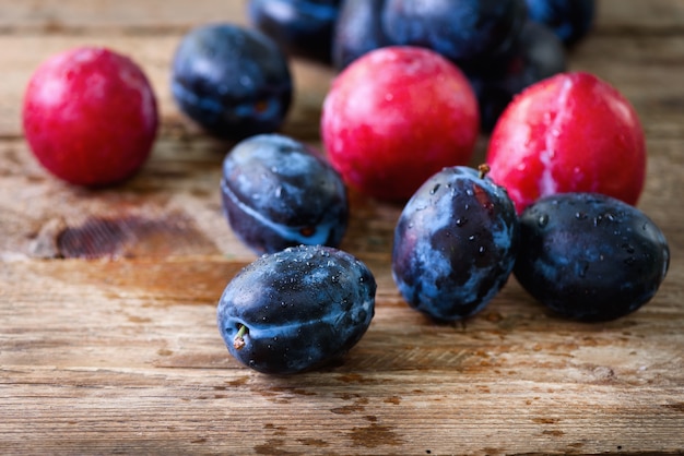 and pink organic plums on dark wooden.