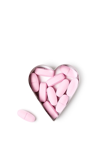 Pink organic vitamin tablets in heart-shaped form on white background, healthy lifestyle concept