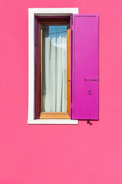 Pink painted facade of the house and window with pink shutters